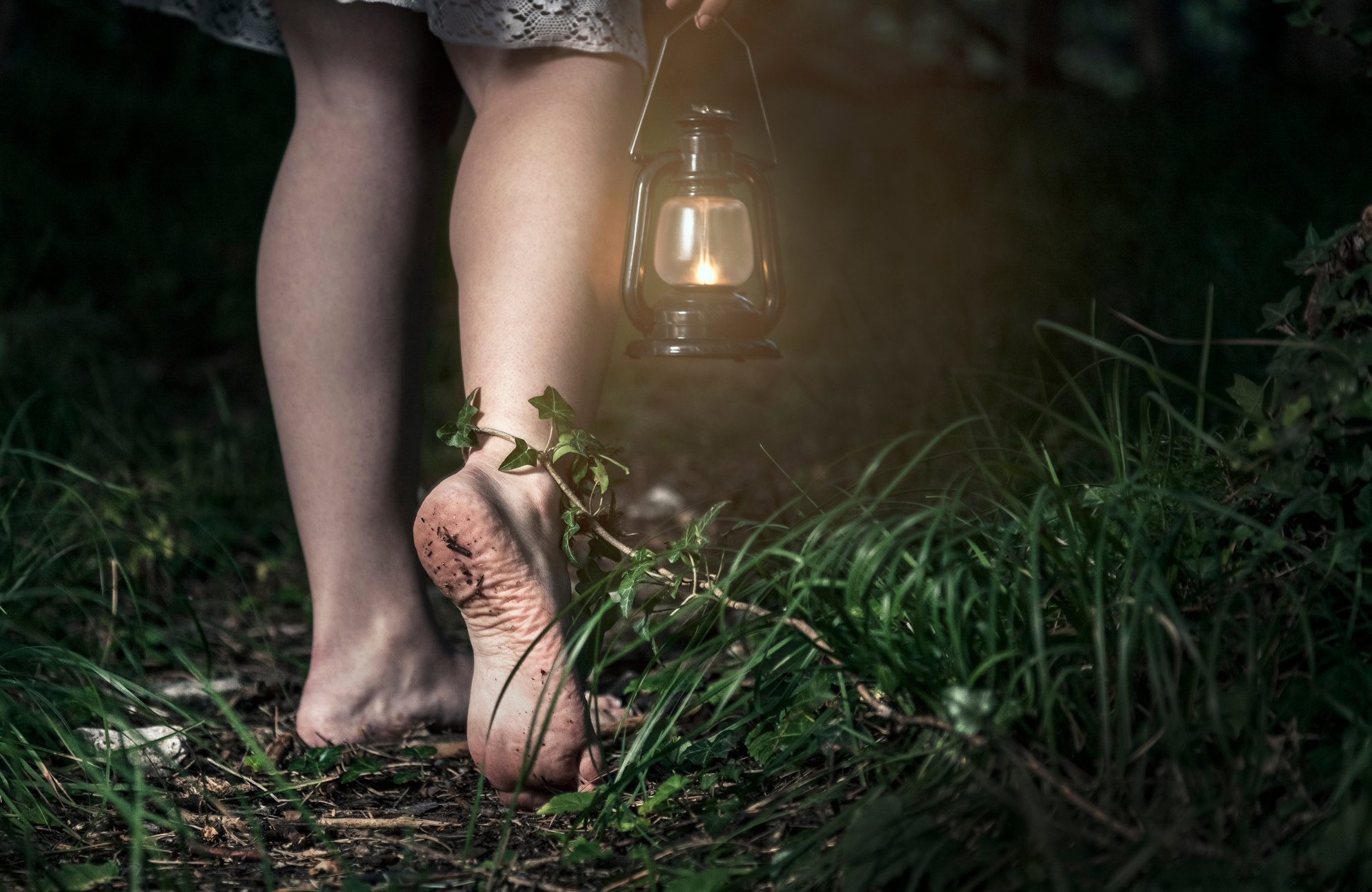 Barefoot woman with lantern in the forest